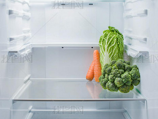 Fresh broccoli, Beijing cabbage and carrots in an empty refrigerator, copy space