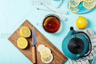 Black tea in glass cup served with fresh lemons over a cyan texture background. Top view. Copy Space