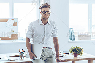 Handsome man in glasses holding laptop 