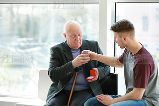 Male caregiver giving pills to senior man in nursing home