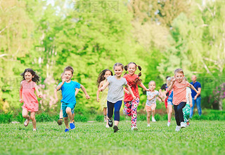 Many different kids, boys and girls running in the park on sunny summer day in casual clothes.
