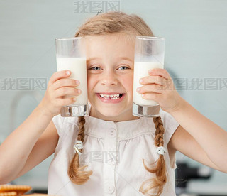 Child drinking milk at home. Happy little girl eating at home