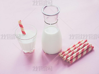 bottle of milk and glass of milk on pink background.