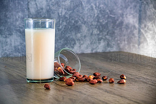 Almond milk with almond on a wooden table and background is bare cement walls