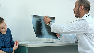 Doctor explaining chest xray image to mother with little daughter