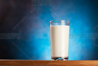 Full glass of milk on wooden table.