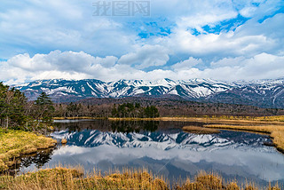 Beautiful lake reflecting blue sky like a mirror, rolling mountain range and woodland in the backgro