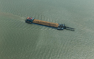 Cargo ship on the river transporting sand on sunny summer day