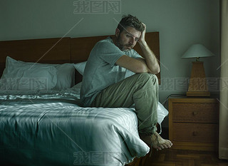 dramatic lifestyle portrait of handsome guy sitting on bed feeli