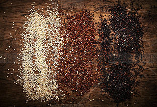 Quinoa set. Black, white and red raw quinoa grains in bowls, groats assorted, wooden rustic kitchen 
