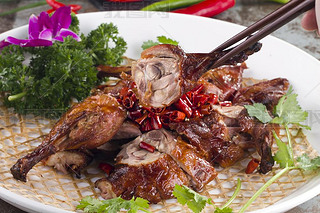 Roast pigeon with dry red pepper in a white dish