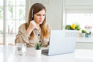 Beautiful young operator woman working with laptop and wearing headseat annoyed and frustrated shout