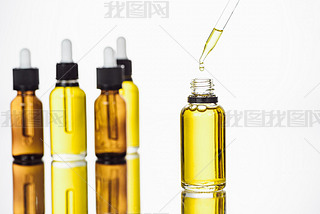 bottles and pipette with natural serum on surface with reflection isolated on white