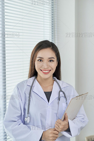 Young doctor or medic with clipboard and stethoscope standing on white background