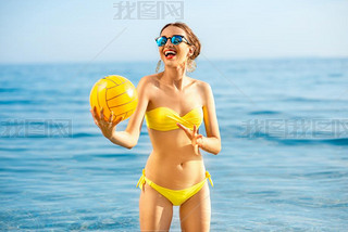 Woman with yellow ball in the sea