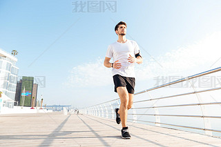 Concentrated young sportan running on pier in the morning