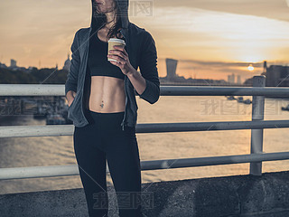 Athletic young woman with cup in London at sunrise