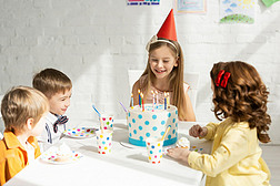 可爱的快乐的孩子们坐在派对桌上吃蛋糕, 同时一起庆祝生日