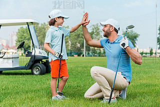 man and son giving high-five on  golf course