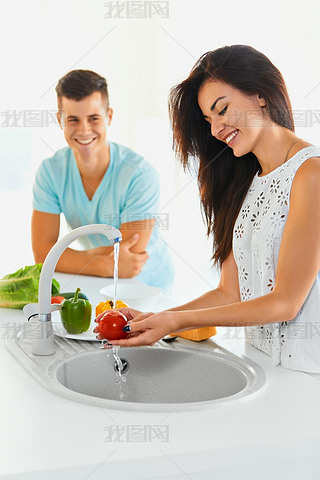 le washing vegetables in the kitchen. Focus on the woman.