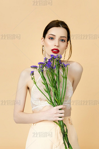 beautiful woman holding purple flowers isolated on beige 