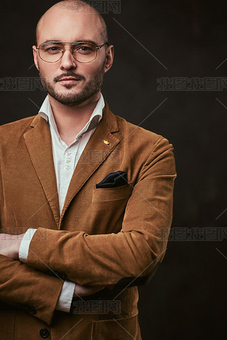 Successfull bald businesan posing in a studio wearing stylish velvet jacket, white shirt and glass