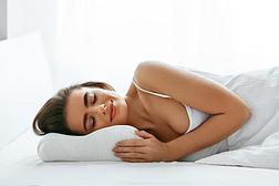 女人睡在白色矫形枕头上, 搁在舒适的床垫上。高分辨率.
