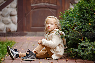 Adorable little curly blond girl in beige knitted sweater ilin