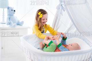 Little girl giving baby brother bottle with milk