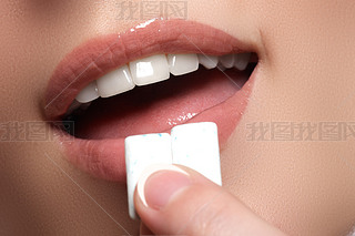Closeup detail of woman putting pink chewing gum into her mouth. Chewing Gum, Eating, Women. Close u
