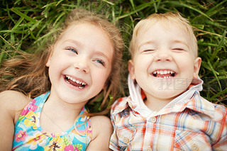 Top view of two kids brother and sister lying on grass