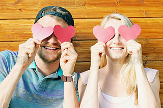 fall in love concept - young couple holding paper hearts over ey