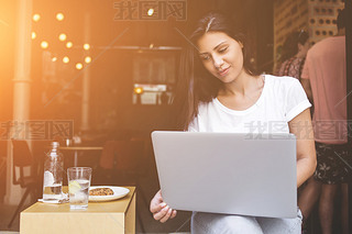 Young female student using laptop computer for learning while sitting in cafe 