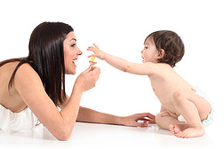 美丽的母亲与她的婴儿用的奶嘴玩