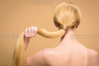 back view of naked blonde woman holding long straight hair isolated on beige