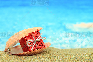 Gift box in a sea shell on the beach