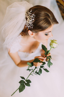 精致玫瑰在手中迷人的年轻女孩穿着洁白的婚纱