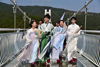 Models dressed in Hanfu or traditional Chinese costume pose on a glass-bottomed bridge in Foshan cit