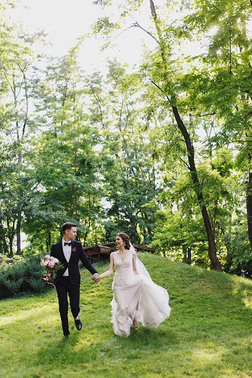 快乐的微笑新郎新娘面面相觑, 在绿色的花园里奔跑。夏天在公园举行婚礼.