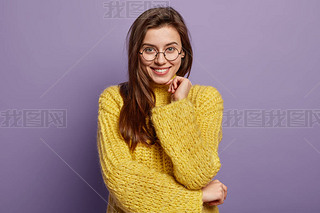 Optimistic pleasant looking woman with appealing appearance, keeps hands partly crossed over waist, 