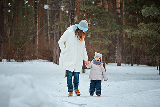Mother and daughter walking in snowy forest