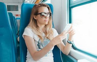Woman on train with phone, student or business woman