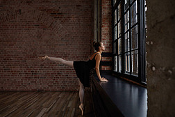 人、芭蕾、艺术和戏剧。美丽优雅的年轻欧洲女芭蕾舞者穿着黑色的短裙, 白色的长袜和尖鞋在宽敞的工作室练习拍摄的照片