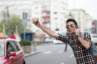 Young man on the street of big city , tries to catch taxi. Carry backpack on one shoulder, street, p