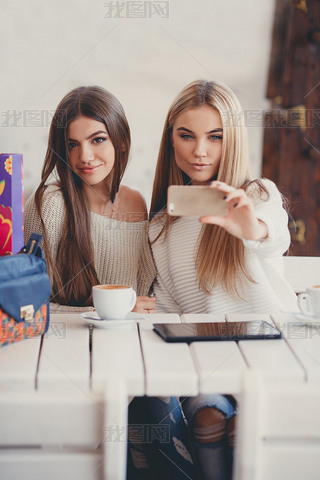 Two young women at cafe looking at pictures of new gadgets