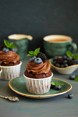 巧克力杯蛋糕,带有巧克力奶油和新鲜浆果.