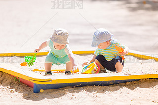 Two baby boys playing with sand