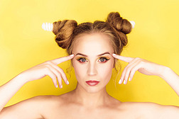 年轻的美女女孩与发角电灯发型在黄色背景
