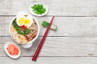 Asian noodle ramen soup with chicken, vegetables and eggs on wooden background. Top view flat lay wi