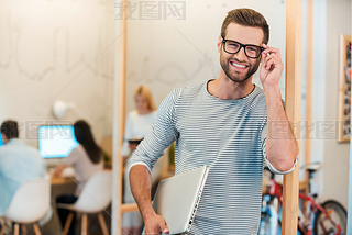 man carrying laptop and adjusting his eyeglasses